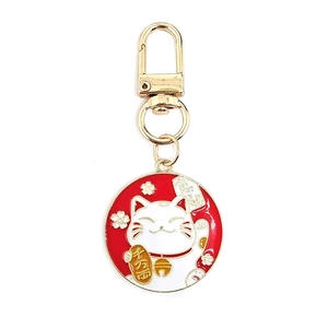 Close-up of red enamel Maneki Neko lucky cat keychain with cherry blossom details