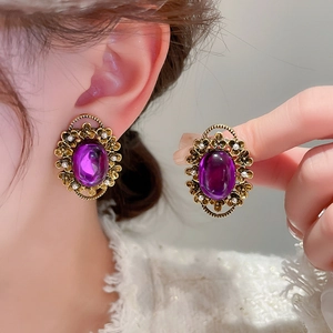 Detailed macro of vintage purple oval gem earring with gold floral base and small pearls