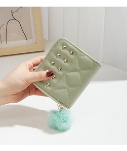 Détail du portefeuille matelassé vert menthe avec clous dorés et breloque pompon doux