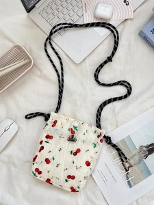 Floral canvas crossbody phone bag with cherry print and woven rope strap on white fabric