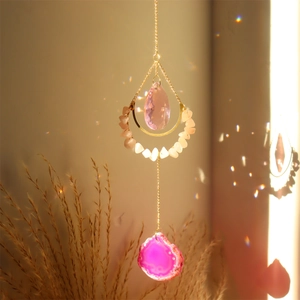 Pink agate suncatcher with crescent moon frame and crystal drop creating rainbow reflections