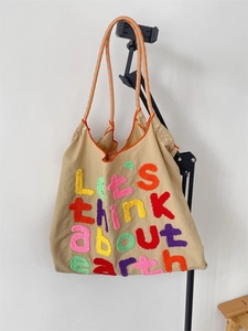 Detail of colorful towel embroidery and orange polka dot strap on a canvas tote bag