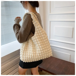Close-up of beige shoulder bag featuring unique bubble pleated texture and minimalist style
