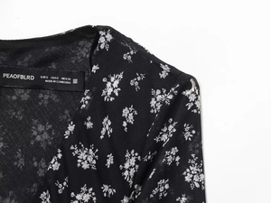 Detail van de halslijn en schouder op een zwarte chiffon jurk met bloemenprint
