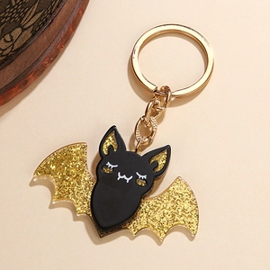 Close-up of black acrylic bat keychain with golden glitter wings and a metal ring