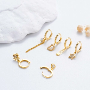 Luxury 6-piece gold earring set with star charms and pearl drops on textured surface