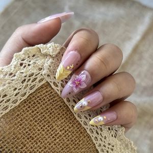 Almond fake nails with 3D cherry blossoms, pearls, and gold glitter stars on model