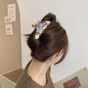 Large marble pattern acetate hair claw clip worn by a model in a cozy home setting