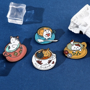 Flat lay of colorful cat and rabbit enamel pins in coffee cups on a dark blue background