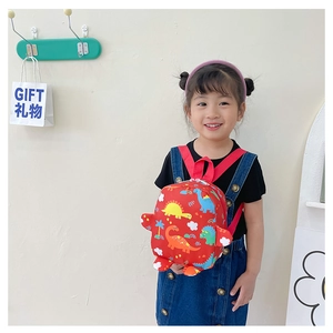 Close-up of kids red dinosaur backpack with colorful cartoon patterns and nylon straps