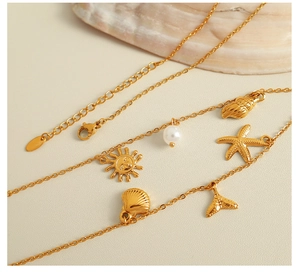 Detail of 18K gold plated necklace featuring sea shell, starfish and pearl pendants