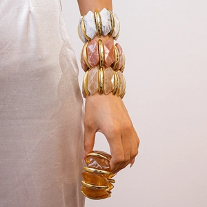 Détail de bracelets épais en acrylique avec motifs marbrés et ambrés sur le poignet
