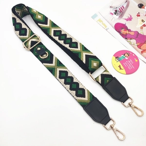 Detail of adjustable woven phone strap with green geometric pattern and gold buckles