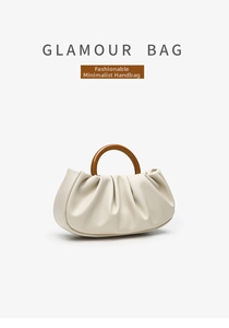 Detail of a beige ruched cloud bag featuring a large brown resin ring top handle