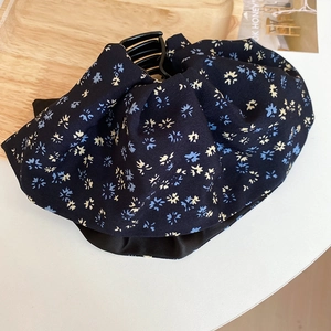 Detail of floral fabric bow hair claw clip with blue pattern on a wooden tray
