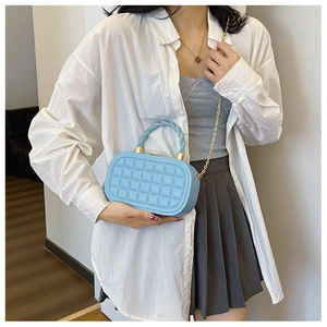Detail of light blue quilted mini box bag with gold chain and twisted handle on model