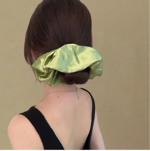 Detailed back view of large green satin scrunchie styled in a classic hair bun