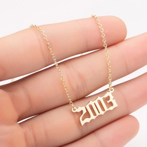 Close-up of golden gothic year 2003 pendant on a delicate stainless steel chain