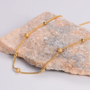 Minimalist gold beaded necklace with polished and frosted beads on a pink quartz stone