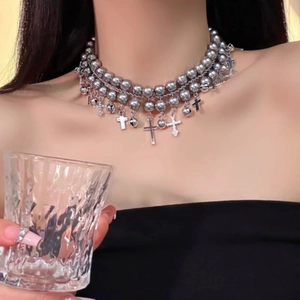 Multilayer silver beaded choker necklace with metallic cross pendants on a female model