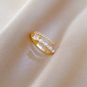 Detailed close-up of an adjustable gold ring with pearls and zircon on champagne silk