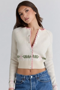 Detail of knit cardigan with pink wavy trim and floral bow embroidery patterns