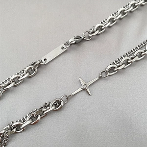 Detail view of silver layered chain necklace with cross pendant and square tag charm