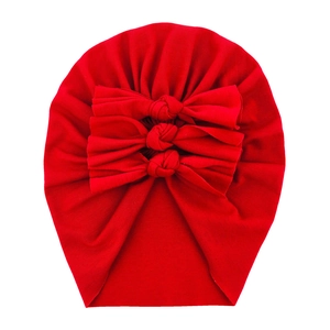 Soft red cotton baby turban hat featuring three decorative bows on a white background
