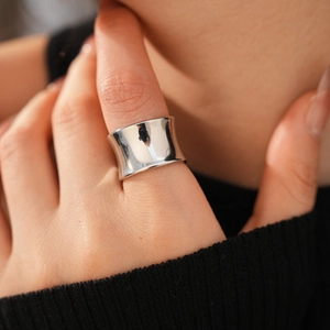Close-up of minimalist wide concave silver ring with polished finish on model's finger