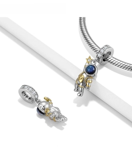 Macro detail of S925 sterling silver astronaut charm with blue glitter and gold accents