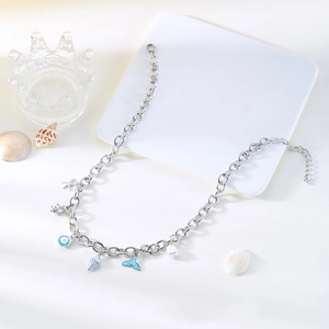 Detail of silver ocean charms featuring a blue fish tail and pearl on a chunky chain