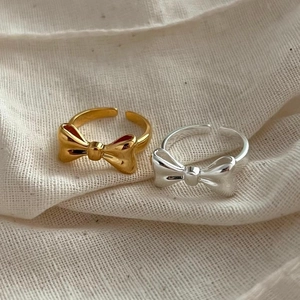Detailed close-up of gold and silver bow rings with adjustable open band design