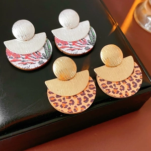 Detail of round wood resin drop earrings in silver and gold metal with abstract patterns