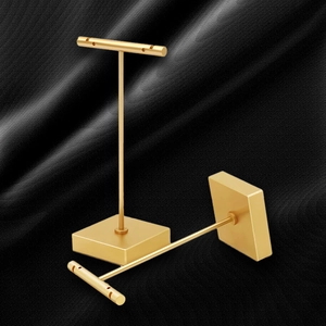 Matte gold T-bar earring display stand with weighted base on elegant black silk background