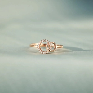 Macro shot of rose gold interlocking double rings with shimmering zircon micro-inlay