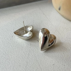 Macro detail of 925 sterling silver heart earrings showing polished texture and studs