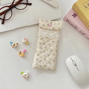 Detail of cream quilted glasses pouch featuring purple floral print and heart button