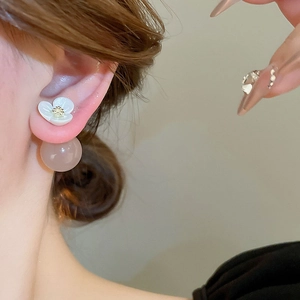 Macro view of white resin flower earrings with semi-transparent round bead pendants