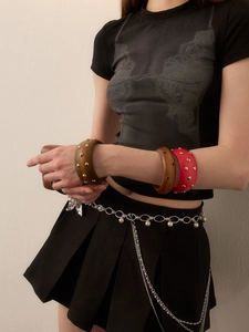Close-up of vintage wide wooden bangles with silver studs and layered pearl chain belt