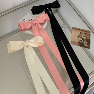 Oversized satin bow hair clips in cream, pink, and black with long ribbon streamers