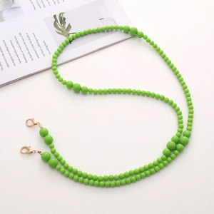 Close-up of green beaded crossbody chain with golden lobster clasps on white background