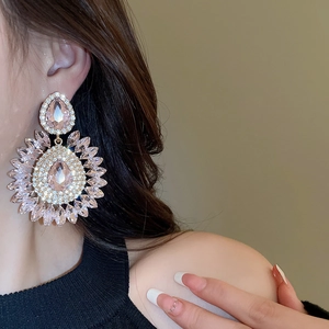 Close-up of sparkling pink crystal teardrop earrings worn by a model in soft lighting