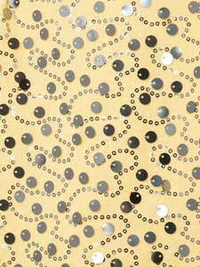 Macro detail of sequin fabric with silver wavy patterns on a soft yellow background