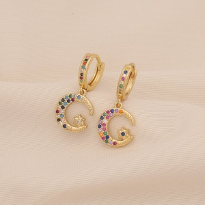 Detailed macro view of gold moon and star earrings with colorful zircon insets