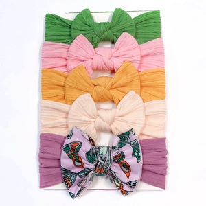 Close-up of a 5-piece set of nylon baby headbands with assorted bows on a white card
