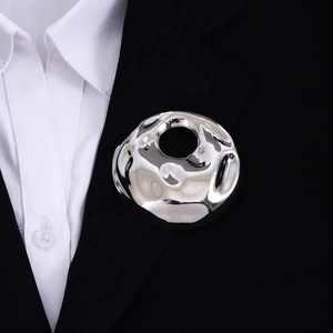 Detailed macro view of a silver irregular round brooch on a black suit lapel