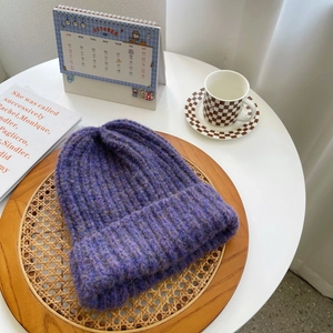 Detailed texture of thick purple chunky knit beanie hat in a cozy setting