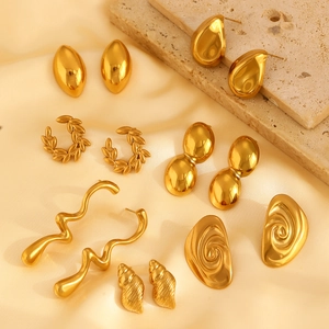 Golden irregular water drop earrings in stainless steel on light yellow silk backdrop