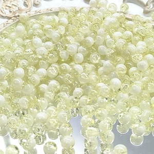 Macro detail of 10mm yellow cracked glass beads for DIY jewelry making on white tray