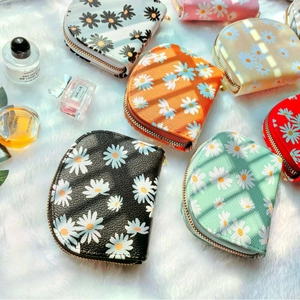 Chic daisy floral coin purses in various colors on a soft white plush background